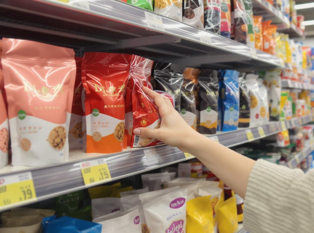 Consumer selecting premium dual finish pouch from crowded retail shelf display