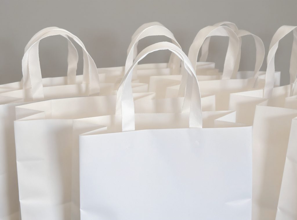 Flat paper handles on white shopping bags showing economical design and construction